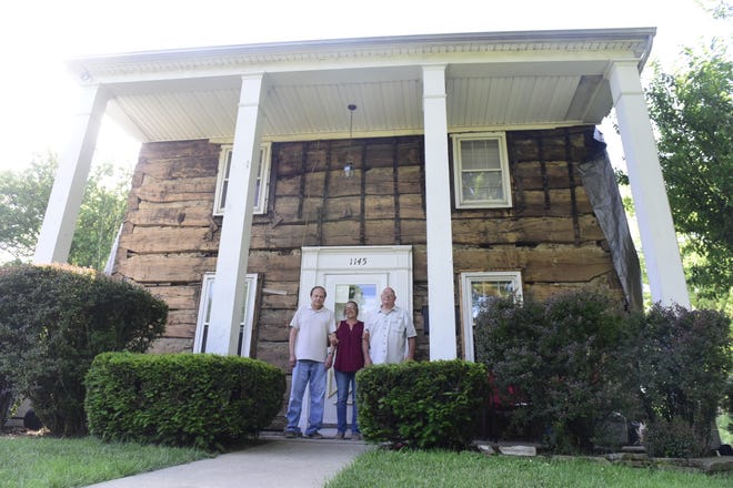 Chuck Richard, Darla Donnenwirth and Mike Donnenwirth stand in front the two-story log home that was built in 1821 and uncovered this spring along Marion Road in Bucyrus.