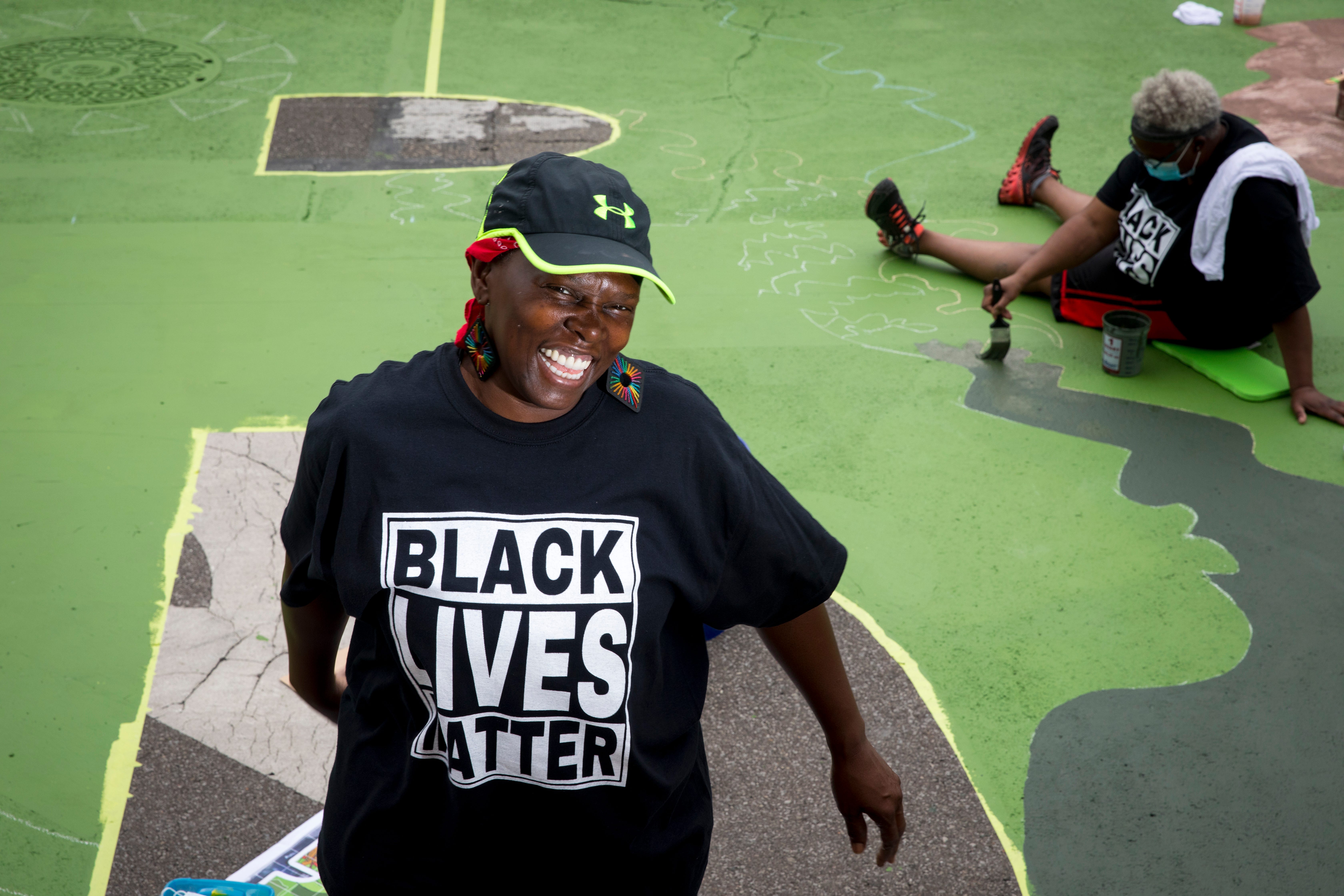 Annie Ruth stands next to the letter "R" that she is creating as part of a bigger mural that reads "Black Lives Matter!" Thursday, June 18, 2020, on Plum Street in front of City Hall in Cincinnati. Seventeen local Black artists were charged with designing and creating a letter to be part of the mural.