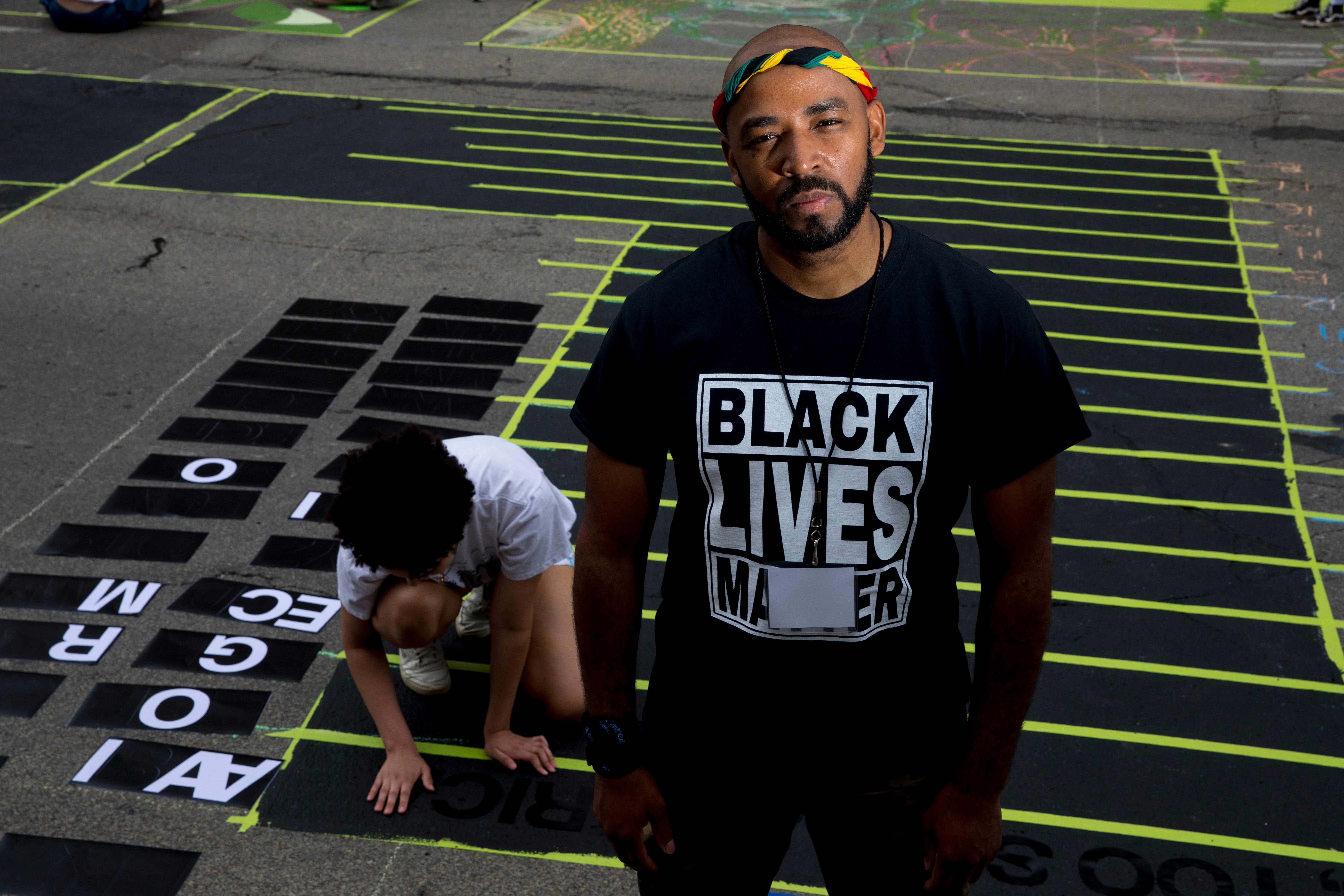 Gee Horton stands next to the letter "L" that he is creating as part of a bigger mural that reads "Black Lives Matter!" Thursday, June 18, 2020, on Plum Street in front of City Hall in Cincinnati. Seventeen local Black artists were charged with designing and creating a letter to be part of the mural.