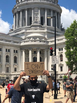 Devon Snyder holds up a sign that reads "I can't breathe" in front of the Wisconsin Capitol while protesting police brutality in Madison.