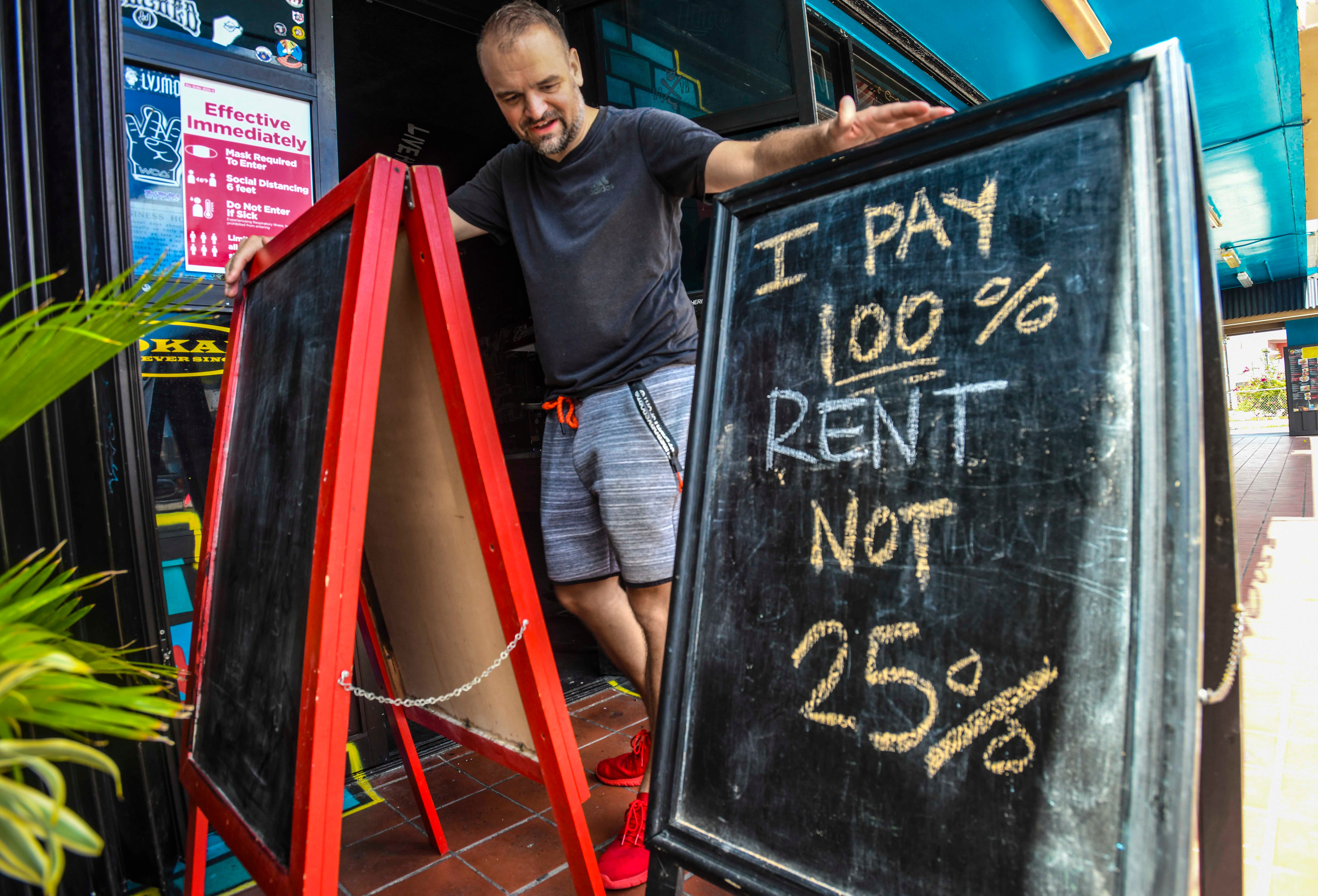 Owner Thomas Peinhopf checks over one of two signs that expresses his sentiment regarding patron limits, posted just outside his Livehouse Guam bar in Tumon in this June 18, 2020, file photo.