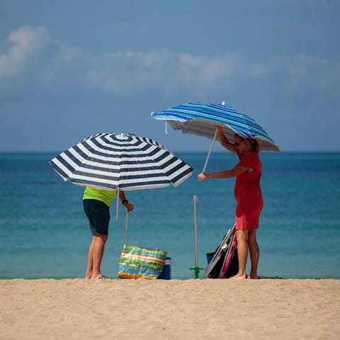 A couple adjust sunshades at the beach of Palma de