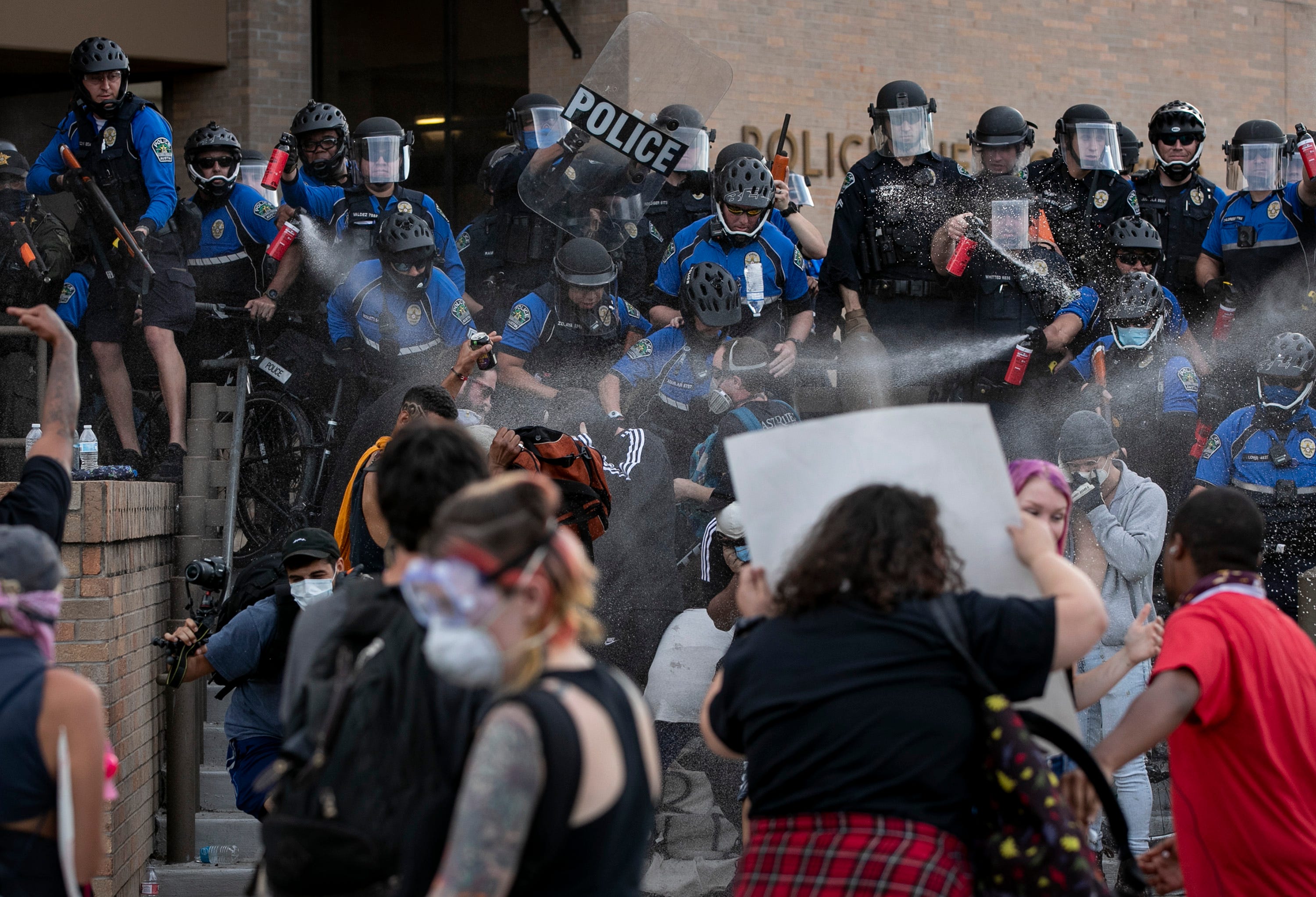 Police and protesters clash at the Austin Police Department Headquarters on Saturday May 30, 2020, during a protest of the death of George Floyd while in custody of the Minneapolis police. Protesters threw water bottles at the police, and police responded with pepper spray and less-lethal rounds.