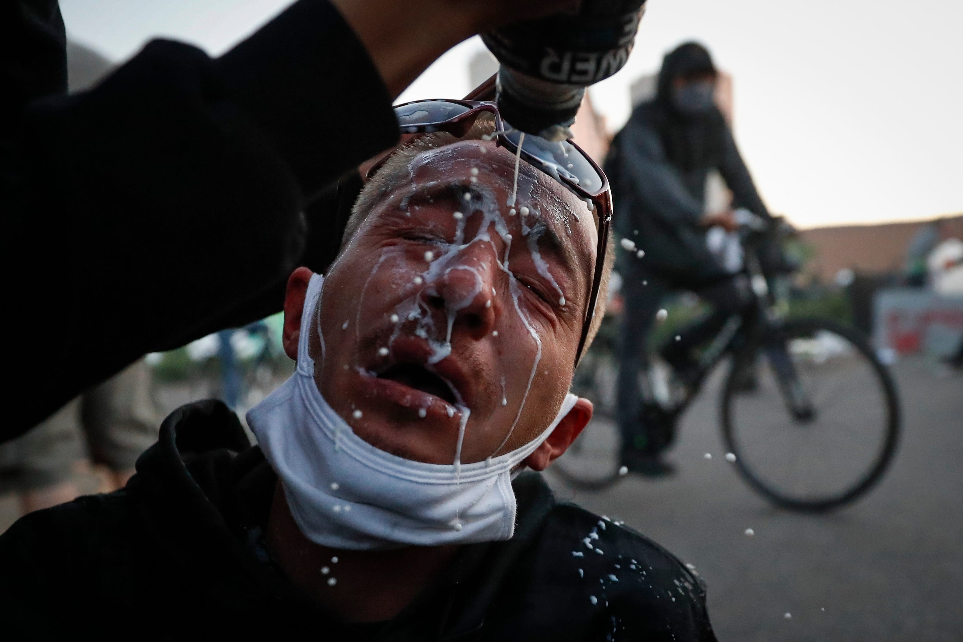 A protester is assisted with a solution to help neutralize the effects of tear gas fired by police outside the Minneapolis 5th Police Precinct, Saturday, May 30, 2020, in Minneapolis.