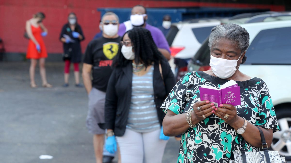 Alcozy Payno-Gamble reads as she waits in line to vote in primary elections at the Nepperhan Community Center in Yonkers, N.Y. June 23, 2020. 