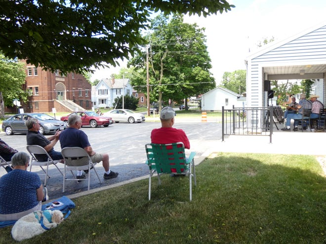 About a dozen seniors gather outside the Crawford County Council on Aging Wednesday to listen to music performed by Harvey & Friends.