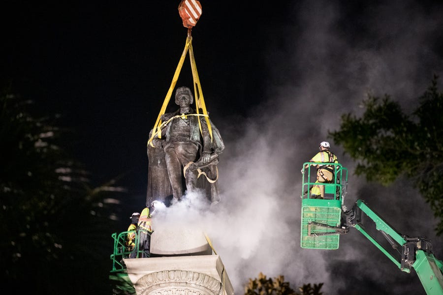 A worker uses a saw at the foot of the statue of John C. Calhoun atop the monument in his honor at Marion Square on June 24, 2020 in Charleston, South Carolina. Work crews began dismantling the monument in Tuesday evening. 