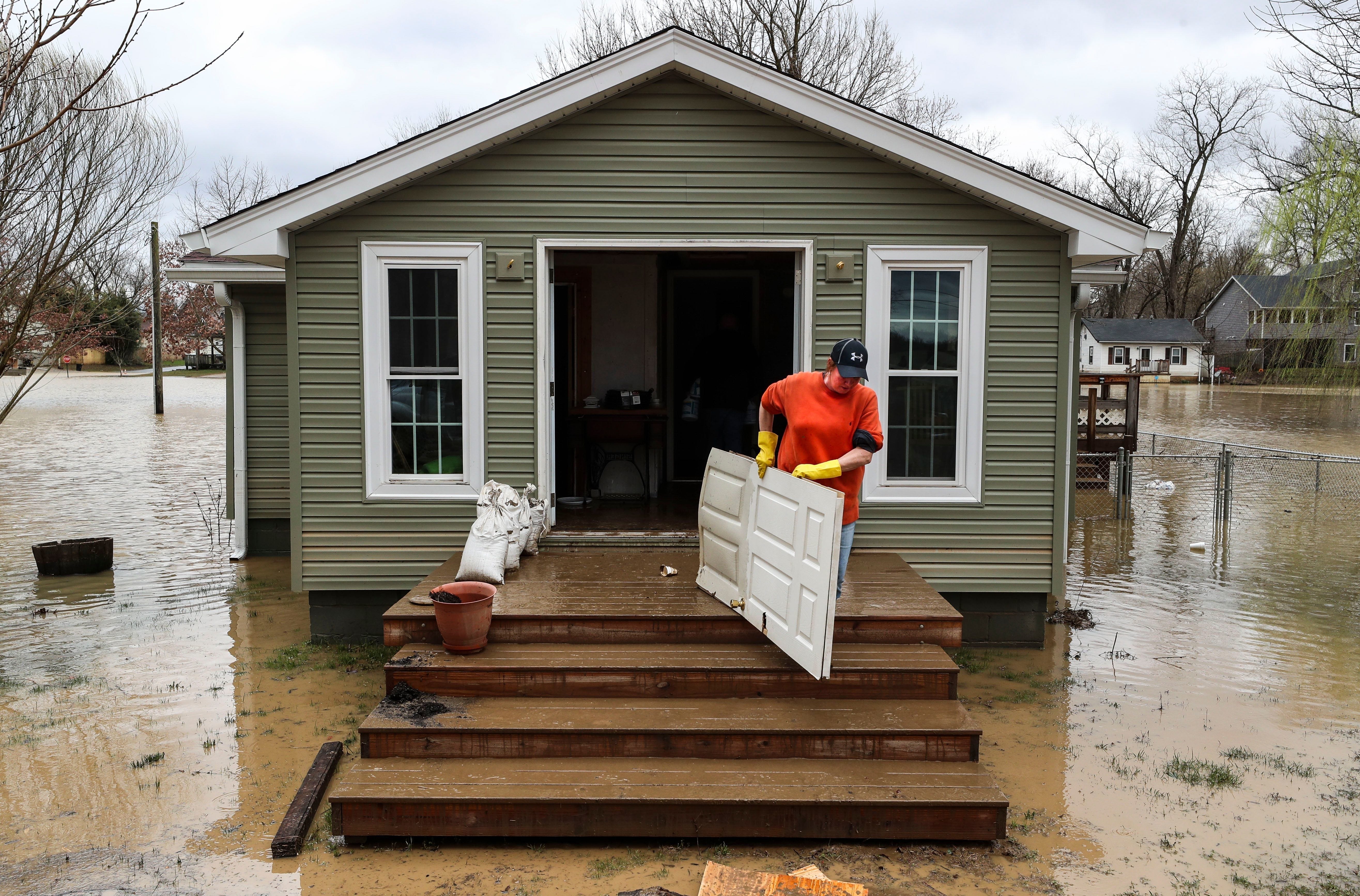 Robin Morrow carries out a flood-damaged door at her home in Utica, IN, on March 1, 2018. Marrows says they'll have to gut the inside but glad the flood wasn't as high as in 1997, where the roof was covered.