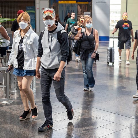 Travelers, some with masks, some without, head awa