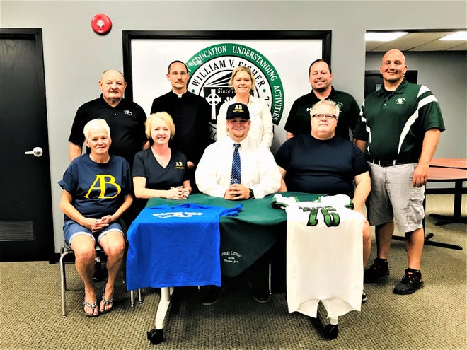 Fisher Catholic's Christian Gaul recently signed to play college football at Alderson Broaddus. He earned All-Ohio honors twice and helped lead the Irish to back-to-back playoff appearances. Seated with  Gaul is his grandmother, Sue Mora and his parents, Bethany and David Gaul. Standing left to right: Fisher Catholic assistant coach John Young, Father Ty Tomson, Gaul's sister, Meredith, Fisher Catholic principal Jim Globokar and Fisher Catholic head football coach Luke Thimmes.