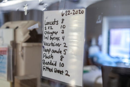 A makeshift whiteboard can be seen in the room of an infectious patient in a Medical Intensive Care pod at Henry Ford Hospital in Detroit, photographed on  June 26, 2020.  Dr. Rana Lee Adawi Awdish says this an example of how the Henry Ford Hospital medical staff adapted during the coronavirus crisis and innovated by writing what supplies are needed in the room so the nurse inside doesn't have to take off and put on PPE to restock. A runner will see the sign in the window and bring the supplies to the nurse so he/she can stay in the room and do everything that patient needs all at once.