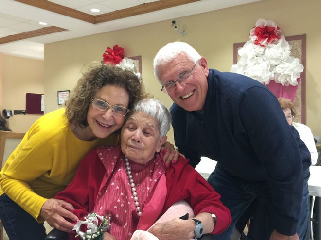 This May 2018 photo provided by Julie Griffith shows Julie Griffith, left, with her mother Mabel Porter, center, and Griffith's husband, David, as they pose for a photo at a nursing home in Oregon, Ohio. The Griffiths are among those advocating to allow cameras inside long-term care facilities. Visitation bans at nursing homes because of the coronavirus have sparked renewed interest in legislation to allow the cameras.(Julie Griffith/Julie Griffith via AP)