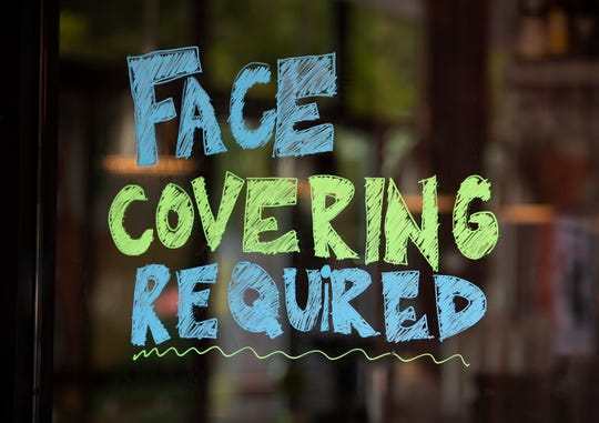 A sign at the entrance of Hopdoddy Burger Bar on South Congress Avenue in Austin, Texas, requires guests to wear a mask on Saturday June 27, 2020, during the coronavirus pandemic.