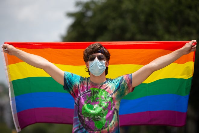 One attendee flies a Pride flag high as a crowd of over 150 gather at the Florida Historic Capitol for a Black Lives Matter and Stonewall Riots anniversary march and event Sunday, June 28, 2020. 