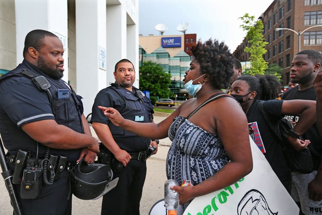 A Milwaukee Police Officer, left, attempts to talk with a protester, right, who said, " They say they want change, but there's no real change," said who didn't want to give her name (but was fine with being photographed). A few dozen protesters protested outside the Milwaukee Police Department on Monday, June 29, 2020 in response to community activist  Vaun Mayes who was arrested by MPD.