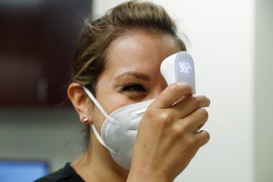 Caring Smiles Family Dentistry dental hygienist Adrienne Vasquez, takes her temperature before the morning briefing to be sure she is OK to see patients on June 30, 2020. The West Bloomfield practice also has patients fill out a COVID-19 questionnaire and have their temperatures taken before they can be seen.