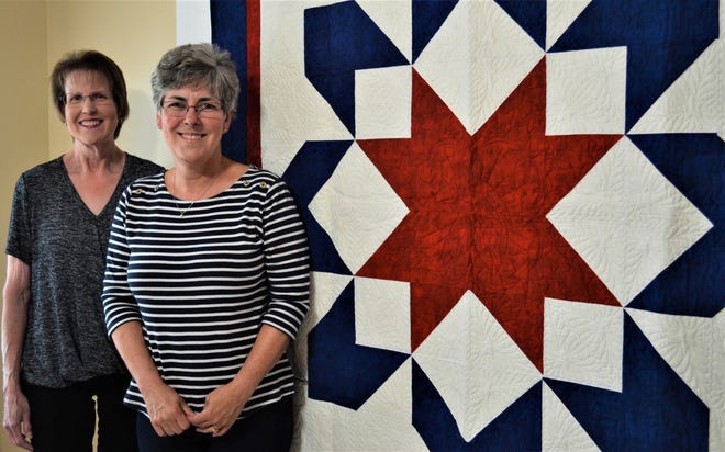 Jill Bothe, left, and Mary Gill stand next to one of the many quilts handmade by the Grateful Valor Girls, the local chapter of the national Quilts of Valor Foundation.  The custom stitching, including eagle in the center, was stitched by “longarmer” Cathi Dix of Huron, who donated her time for the group.