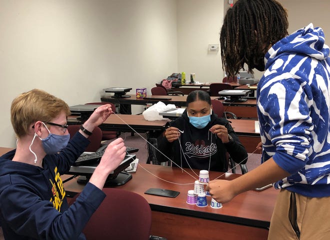 Cameron O'Dell, Tamia Kendrick and Denzel Assogba put together a pyramid with cups and string Thursday, part of a team building exercise at OhioMeansJobs Licking County. Recent high school grads are preparing to work in local manufacturing jobs during the summer.
