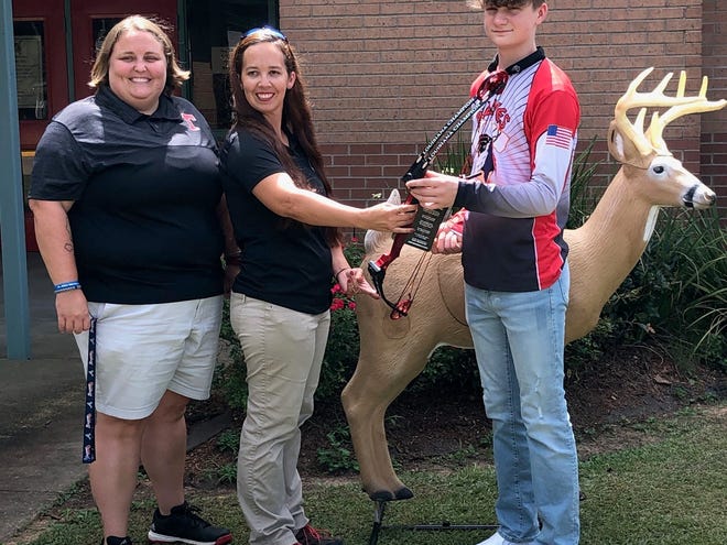 Tioga Junior High’s Jacob Robertson was awarded with his Louisiana State Champion Genesis bow Wednesday. From left are Tioga Junior High coach Holley Pace, Christina Speyer from the Department of Wildlife and Fisheries and Robertson.