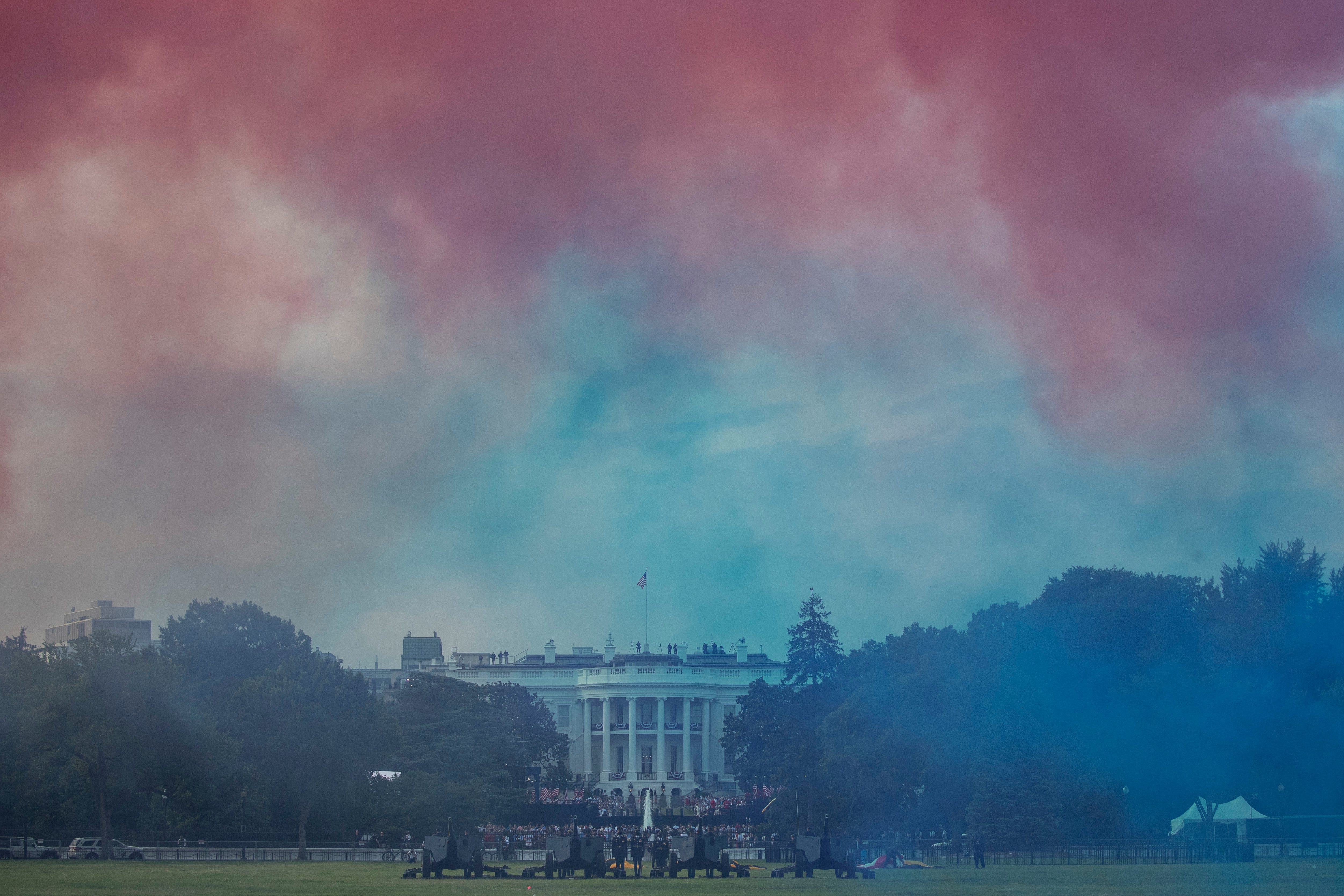 The White House in obscured by Red and Blue smoke floating on the Ellipse during a "Salute to America" event on the South Lawn of the White House, Saturday, July 4, 2020, in Washington.