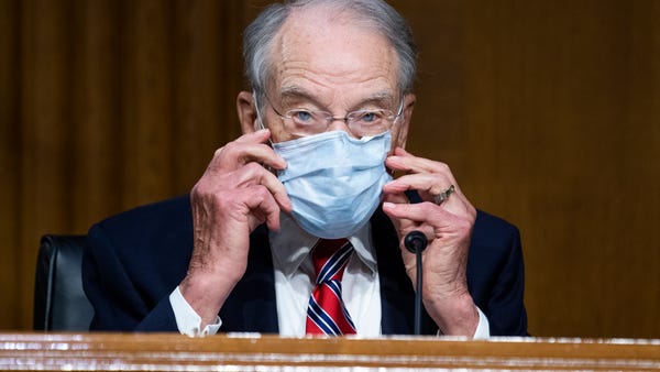 Sen. Chuck Grassley, R-Ia., adjusts his face mask 