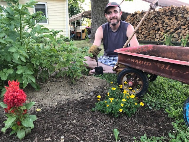 Flanked by potato plants (left), annual flowers in the foreground and his new antique Radio Flyer for yard tasks, Zach Tuggle is 'digging in.'