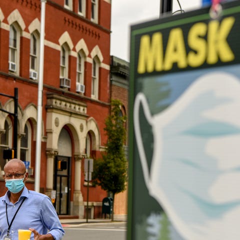 Jorge Meneses wears a mask as he walks by a "Mask 