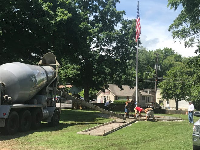 Workers install a sidewalk around a new flagpole erected as part of a memorial to the military and first responders at Clarksville's Historic Greenwood Cemetery.