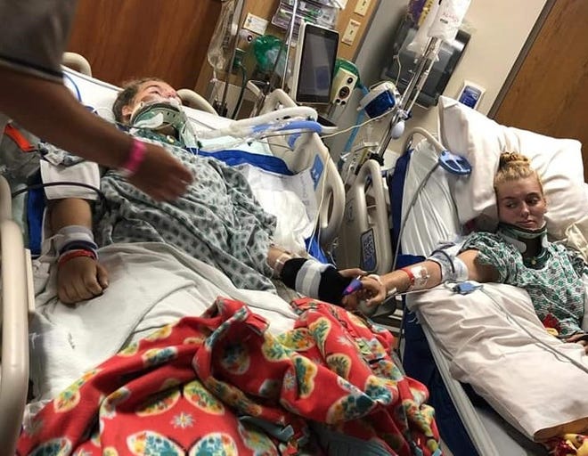 Leah Vanderpool, left, reaches out to hold the hand of her twin sister, Layne, as both recover from injuries they suffered in a June 30 crash on U.S. 30.
