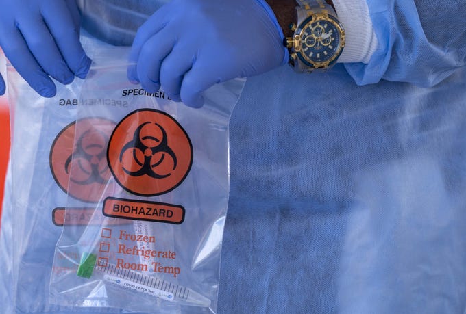 Health care workers take samples for COVID-19 testing in the South Mountain Community College parking lot in Phoenix on July 10, 2020.