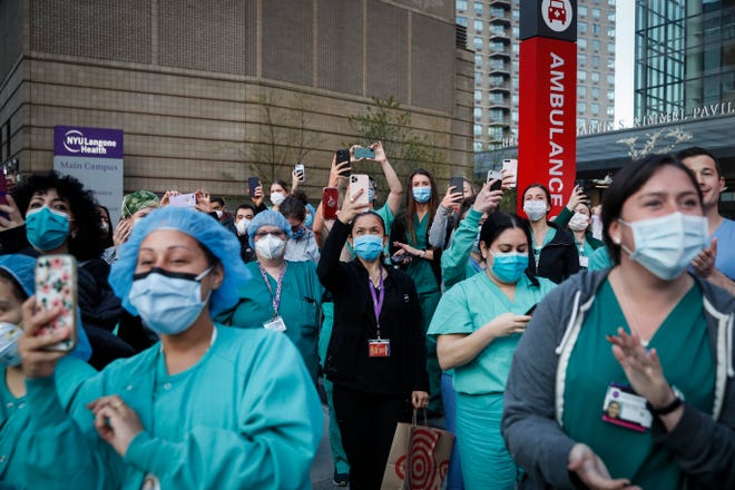 FILE - In this April 28, 2020, file photo Medical personnel attend a daily 7 p.m. applause in their honor, during the coronavirus pandemic outside NYU Langone Medical Center in the Manhattan borough of New York. Essential workers are lauded for their service and hailed as everyday heroes. But in most states nurses, first responders and frontline workers who get COVID-19 on the job have no guarantee they'll qualify for workers' comp to cover lost wages and medical care. (AP Photo/John Minchillo, File)