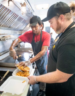 Cook Demitrius Arnold, left, and owner Kendrick Hobbs plate a mac and cheese burger melt July 13 at the new Melt food truck in Pensacola.