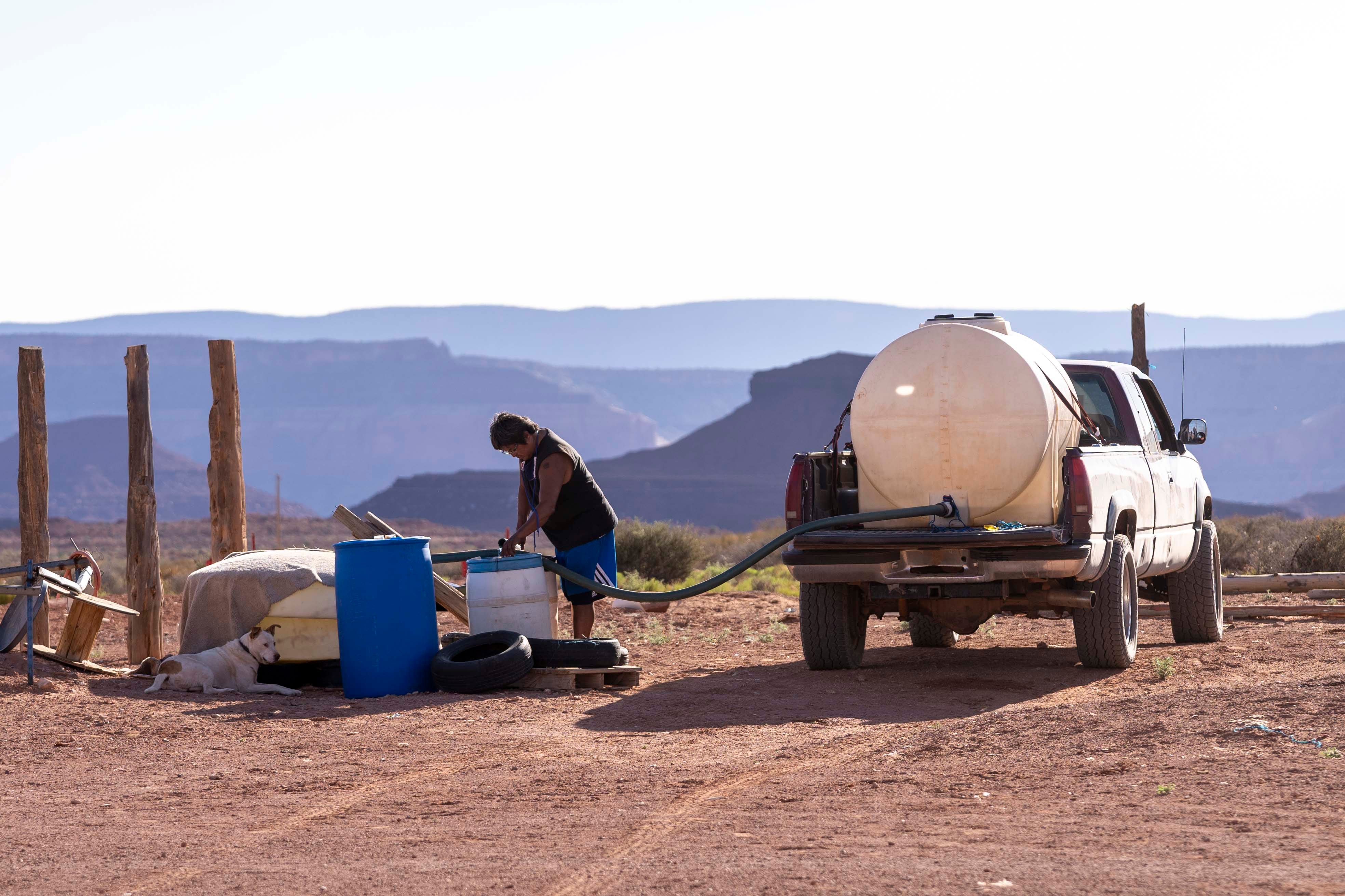 Tommy Rock fills water barrels at his family's home in Oljato, Utah, on the Navajo Nation. Rock is a researcher who specializes in studying environmental contamination and public health.