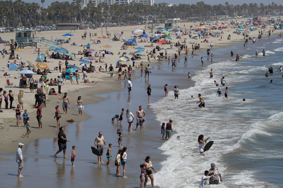 A heat wave has brought crowds to California's beaches as the state grappled with a spike in coronavirus infections and hospitalizations.