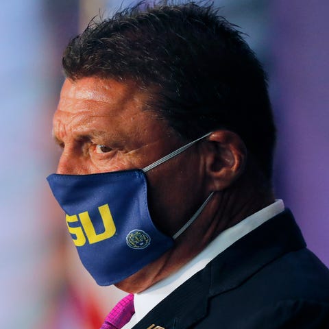 LSU football coach Ed Orgeron wears a mask with th