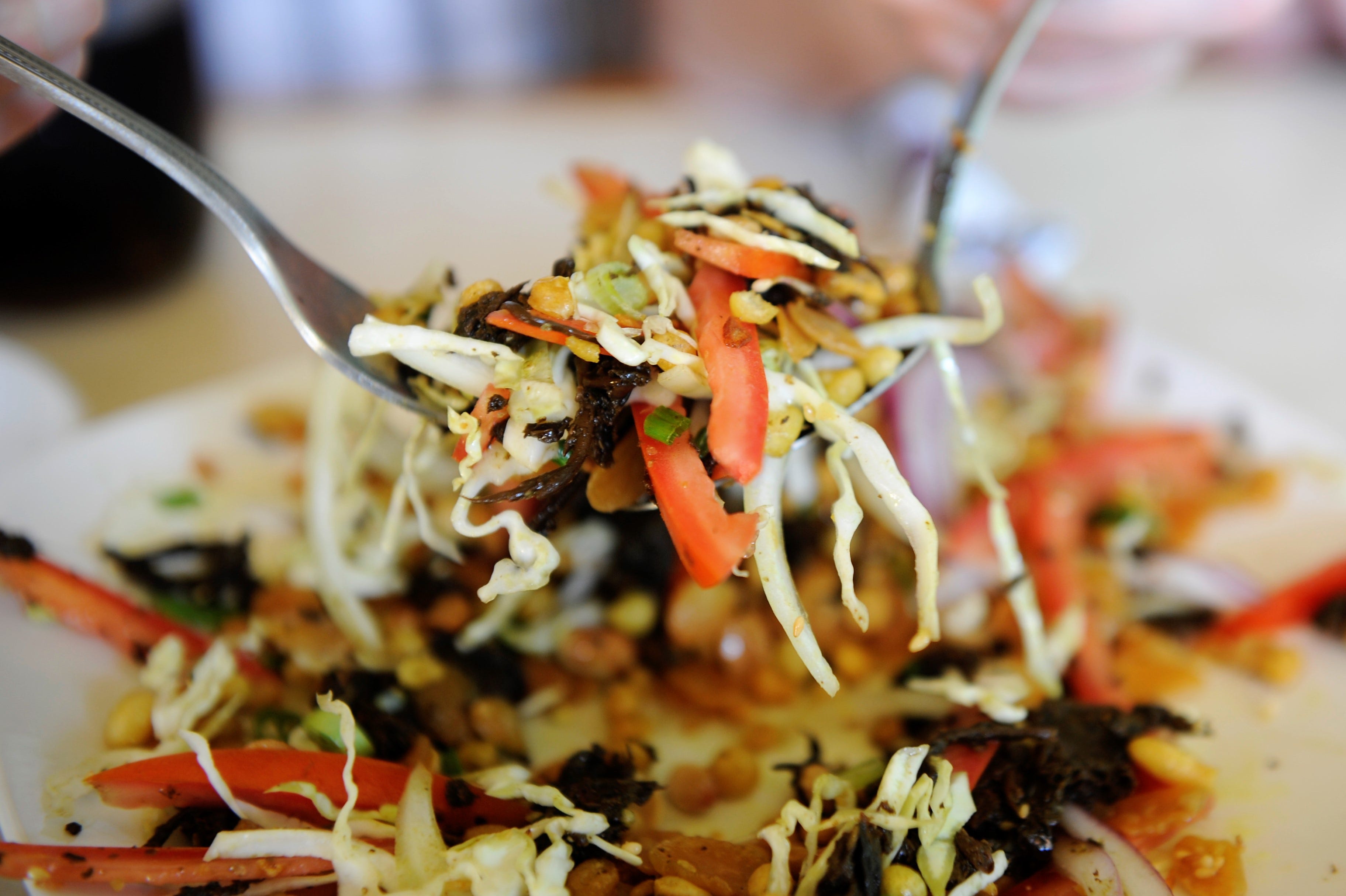 Tea leaf salad with scallion and sliced onion, fermented tea leaves, tomato, cabbage, chile, and toasted nuts and seeds at the Owensboro Karen Restaurant.