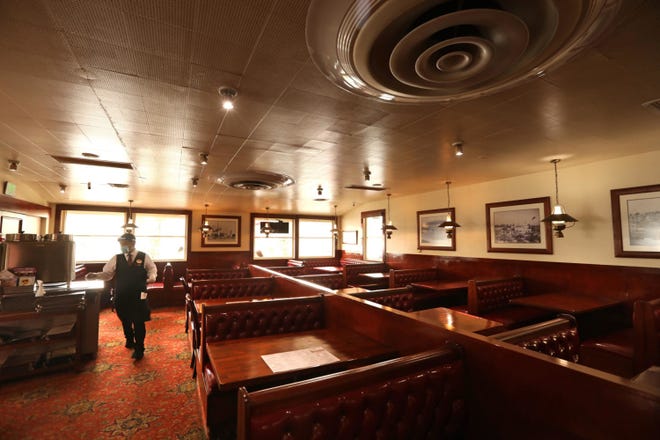 Waiter Junior Martinez, wearing a face shield and mask, walks through the empty dining room of Dupar's Restaurant in Los Angeles on July 1, 2020. (Genaro Molina/Los Angeles Times/TNS)