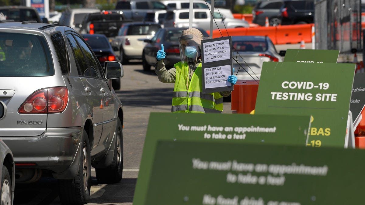 Workers direct cars as they wait in line for coronavirus testing at Dodger Stadium, July 14, 2020, in Los Angeles.