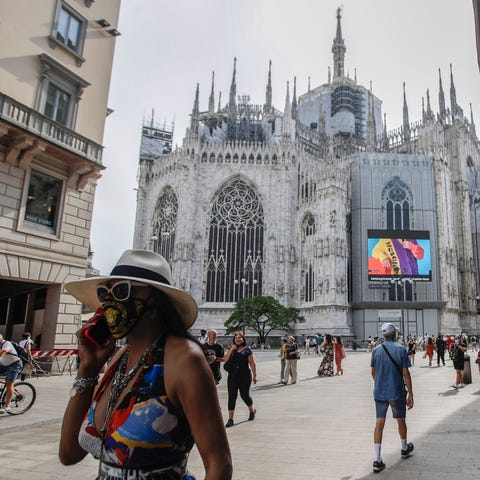 Pedestrians pass by a screen on the Duomo cathedra