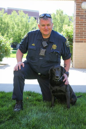 Officer Tom Emmons kneels next to his partner, Bonnie, as they pose for a photo. Bonnie died after being struck by a truck while responding to a shooting on Thursday, July 16, 2020.