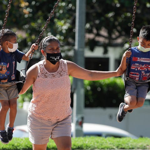 A woman and two children wear masks at a playgroun