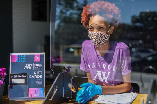 Barista Erika Hicks, 23, of Detroit serves coffee to Cheryl Spears, of Detroit at Narrow Way Cafe and Shop on the Livernois Avenue of Fashion in Detroit on July 17, 2020. Narrow Way recently reopened, but doesn't allow people to come inside, but serves customers through the bay garage door that now has a counter with plexiglass and all personnel wear masks.