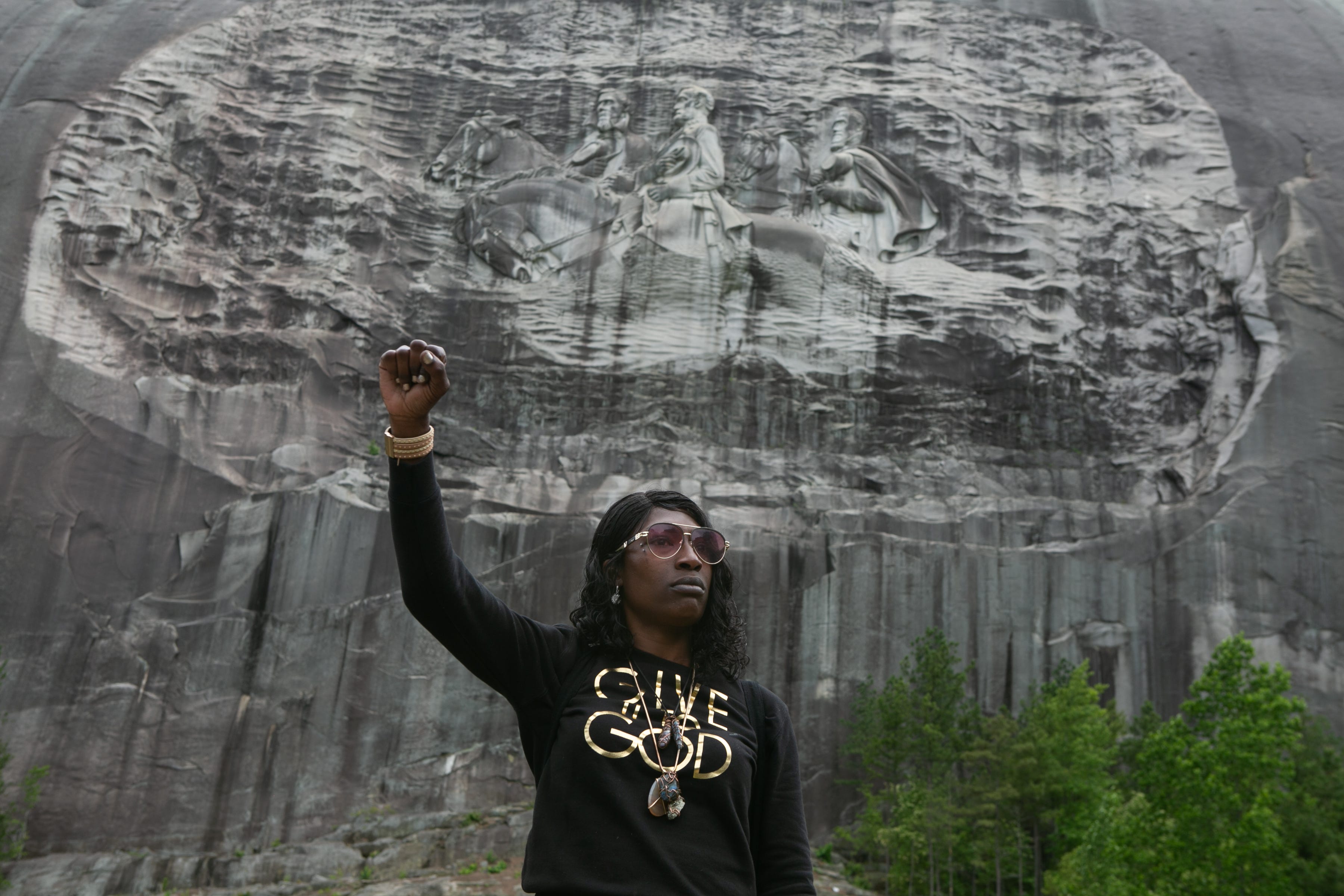 STONE MOUNTAIN, GA - JUNE 16: Lahahuia Hanks holds up a fist in front of the Confederate carving at Stone Mountain Park during a Black Lives Matter protest on June 16, 2020 in Stone Mountain, Georgia. The march is to protest confederate monuments and recent police shootings.  Stone Mountain Park features a Confederate memorial carving depicting Stonewall Jackson, Robert E. Lee, and Jefferson Davis, President of the confederate states.  (Photo by Jessica McGowan/Getty Images)