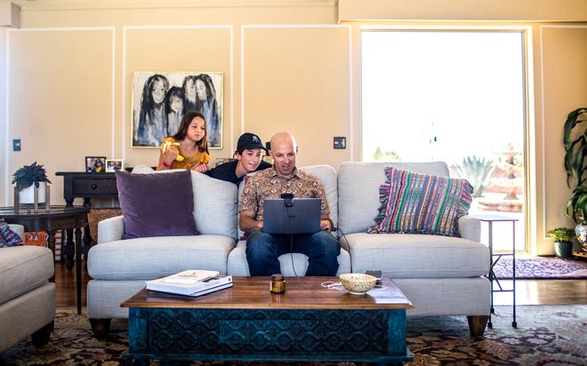 Dave Sbarra, a psychologist and professor at the University of Arizona, conducts his office hours for a class over Zoom in his living room as his children Margot, 9, and Mateo, 12, look over his shoulder, on April 7, 2020.