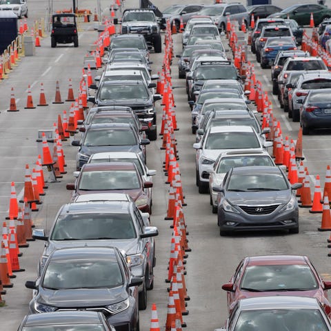 FILE - Cars wait in line at a drive-through COVID-