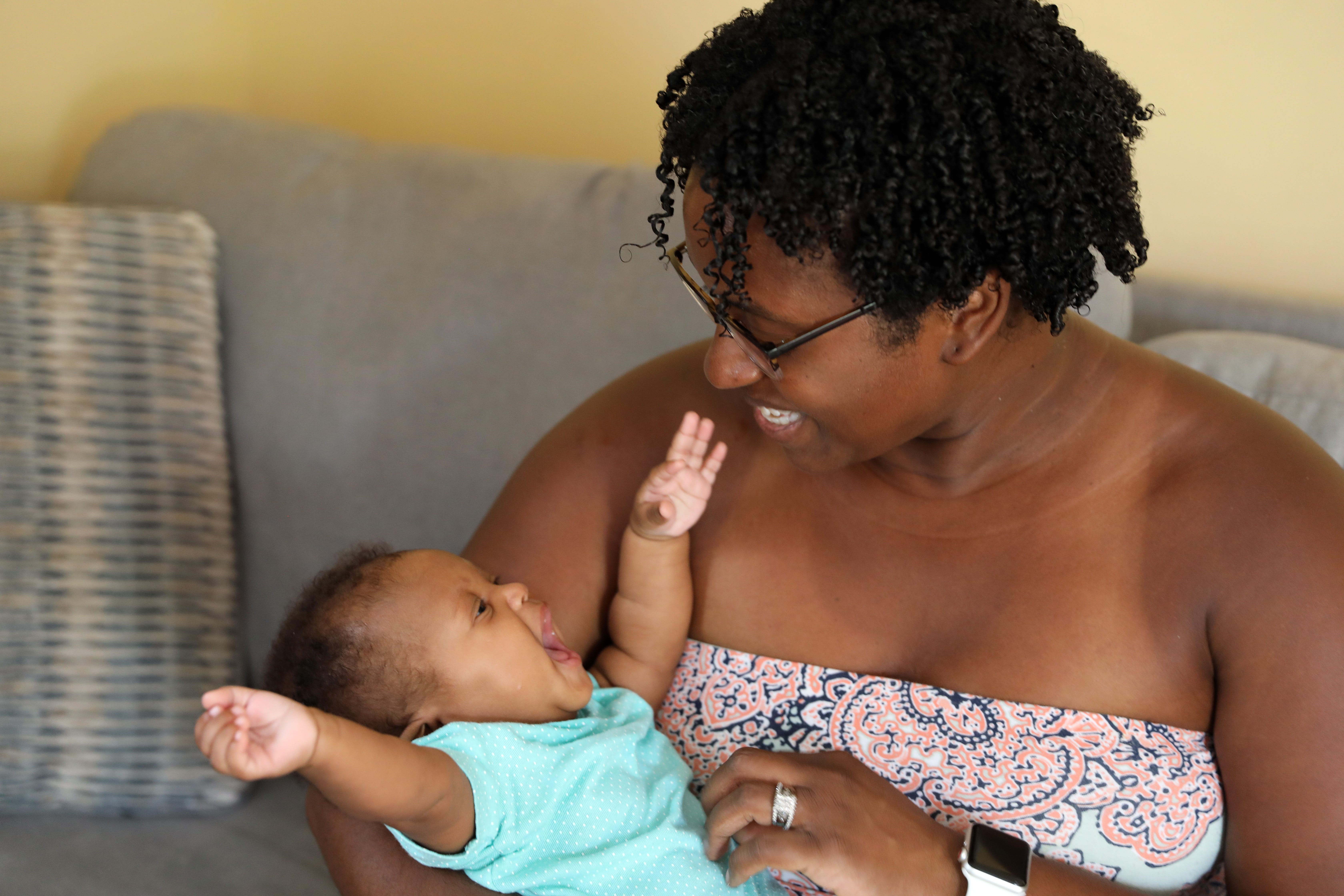 Meredith LeJeune, 37, plays with her three-month old daughter, Mecca. LeJeune, also a mother of twins, said her experience with her first pregnancy with a Black doctor was warmer and more comforting than her second experience with a white doctor, which felt sterile. She wants to become a doula to advocate for other women.