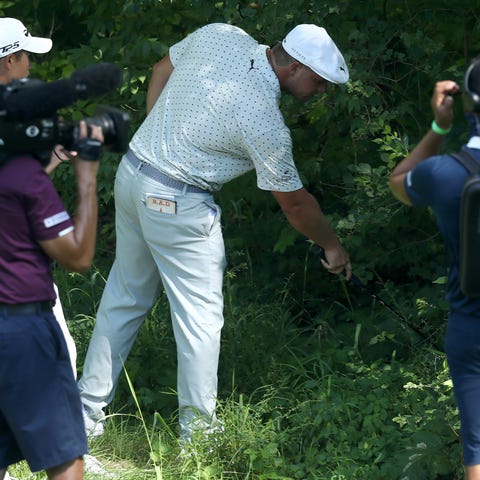 Bryson DeChambeau looks for his ball on the 15th h