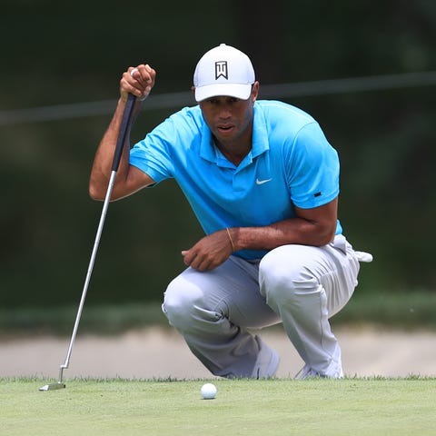 Tiger Woods lines up a putt on the 1st green durin