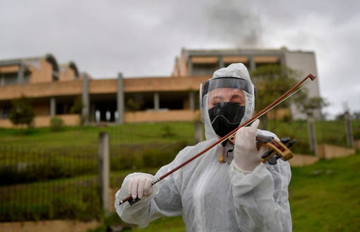 An employee of a funeral home plays the violin during the accompaniment of mourning before the cremation of a victim of the novel coronavirus COVID-19, at the Serafin cemetery in Bogota, on July 17, 2020. - The pandemic has killed at least 590,000 people worldwide, including more than 6,000 in Colombia, since it surfaced in China late last year and more than 13.8 million have been infected, according to an AFP tally at 1200 GMT on Friday based on official sources.