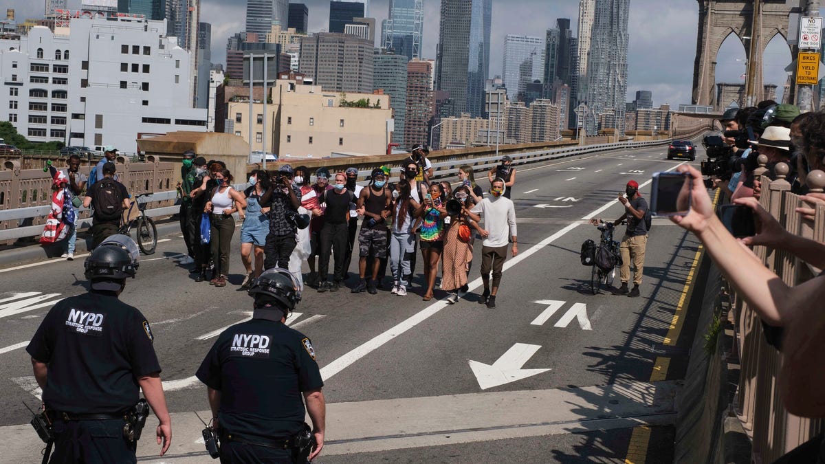 NYPD stand on the Brooklyn Bridge as Black Lives Matter protester Wednesday, July 15, 2020, in New York.  Several New York City police officers were attacked and injured Wednesday on the Brooklyn Bridge during a protest sparked by the death of George Floyd. Police say at least four officers were hurt, including the department's chief, and more than a dozen people were arrested.
